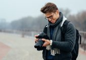 Cheerful handsome man eyeglasses looks photos camera